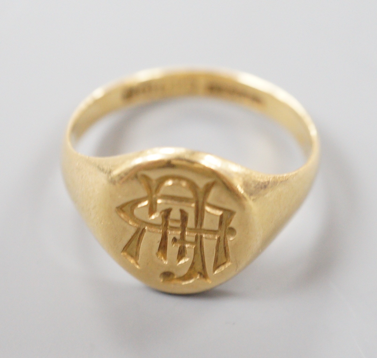 A George V 18ct gold oval signet ring, with intaglio monogram and engraved inscription, size S/T, 8.1 grams.